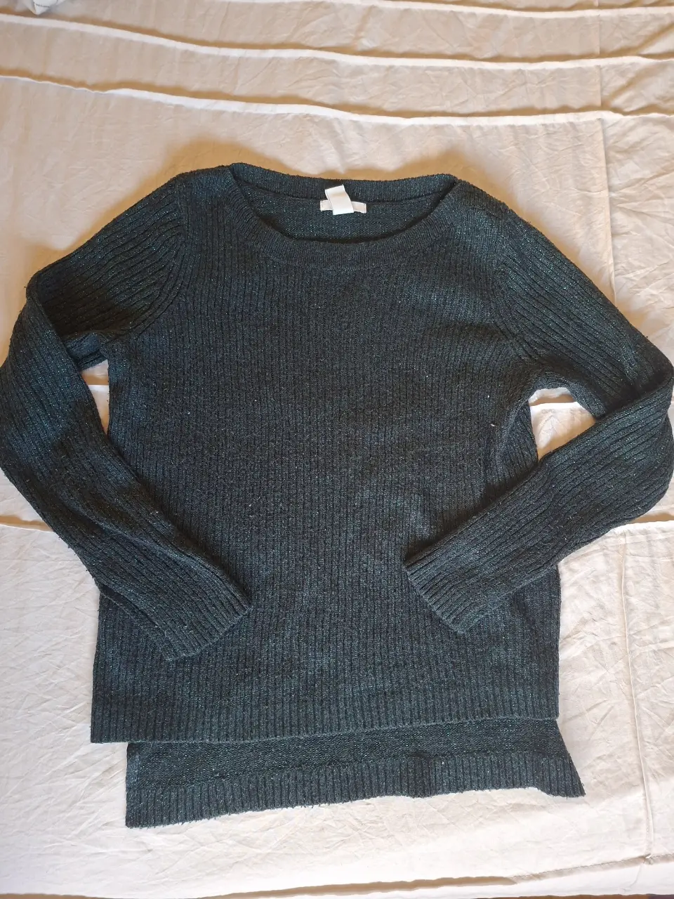 Sweater de punto grueso en color verde oscuro con detalles brillantes. Ideal para un look casual y abrigado en invierno.