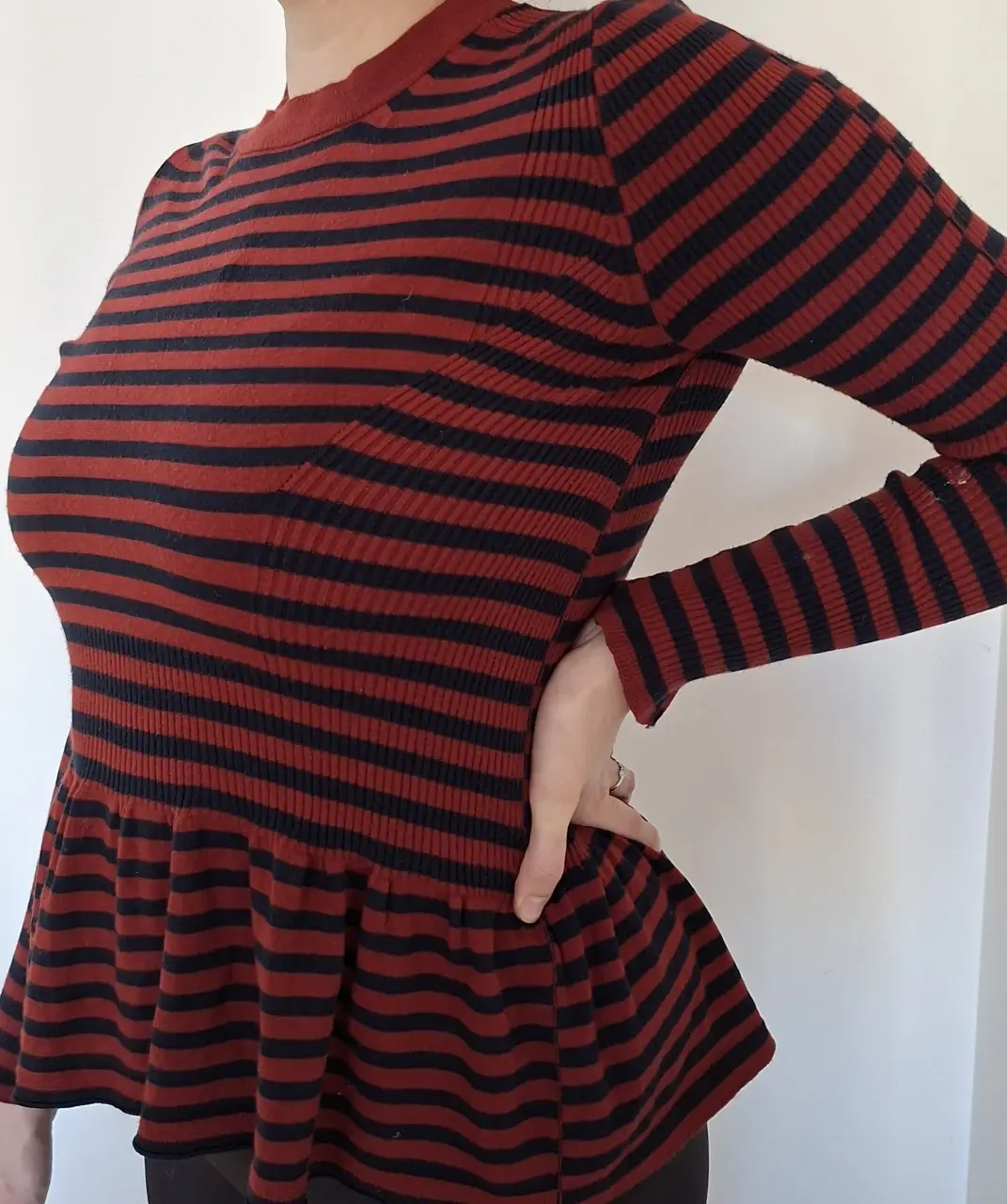 Sweater de mujer a rayas rojas y negras, con cuello alto y corte peplum. Ideal para un look casual y abrigado.