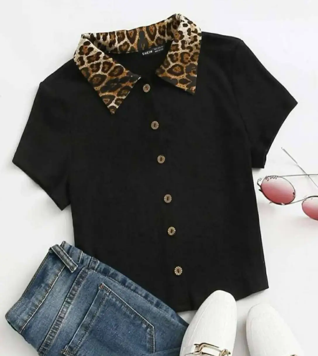 Blusa negra con cuello camisero con estampado de leopardo. Mangas cortas y botones decorativos. Ideal para un look casual con un toque de estilo.