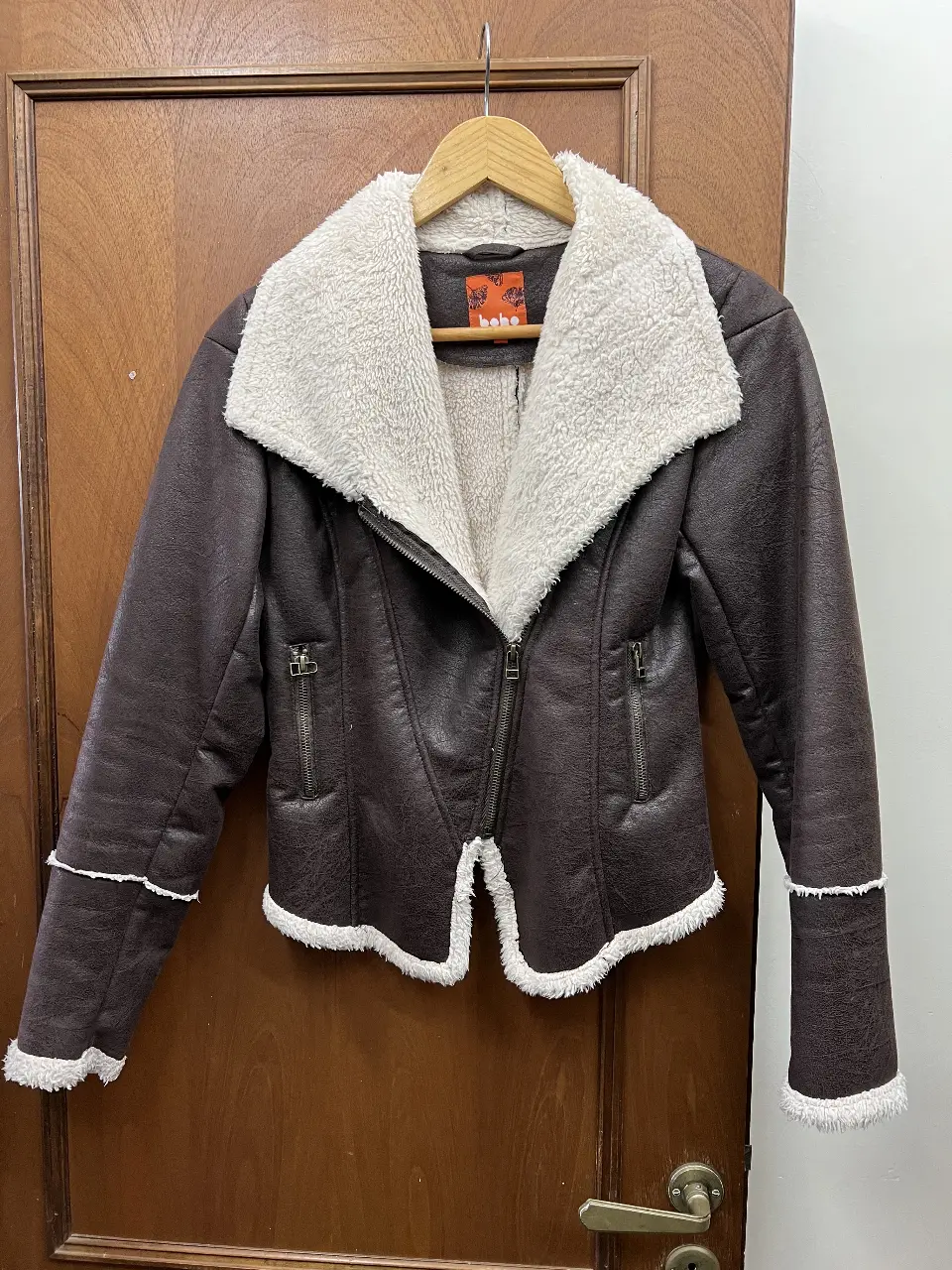 Campera de cuero sintético marrón con detalles en blanco y cuello con piel sintética. Ideal para un look moderno y abrigado.
