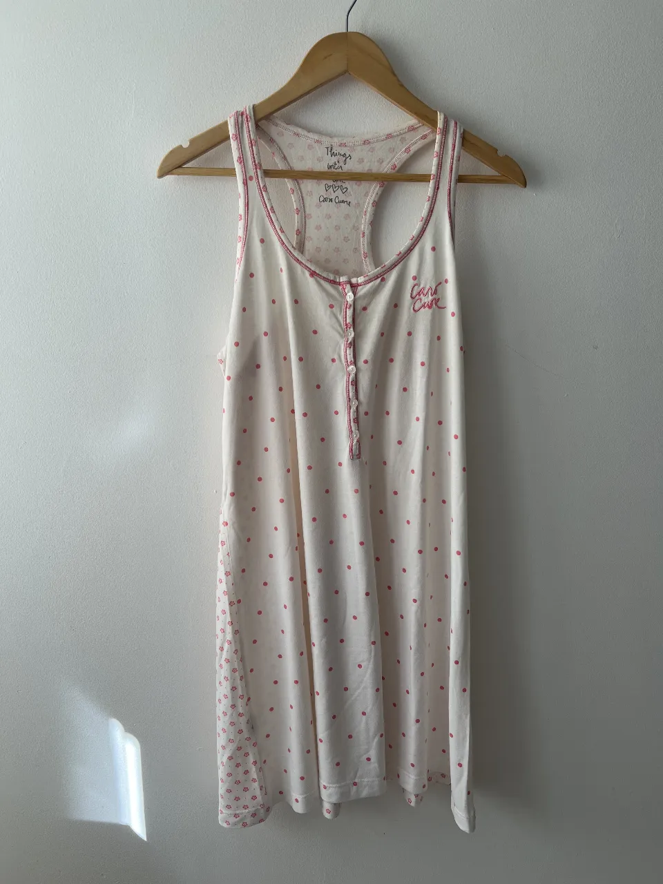 Camisón de dormir para mujer, blanco con estampado de lunares rosas. Diseño con botones y detalles en rosa. Ideal para un descanso cómodo y con estilo.