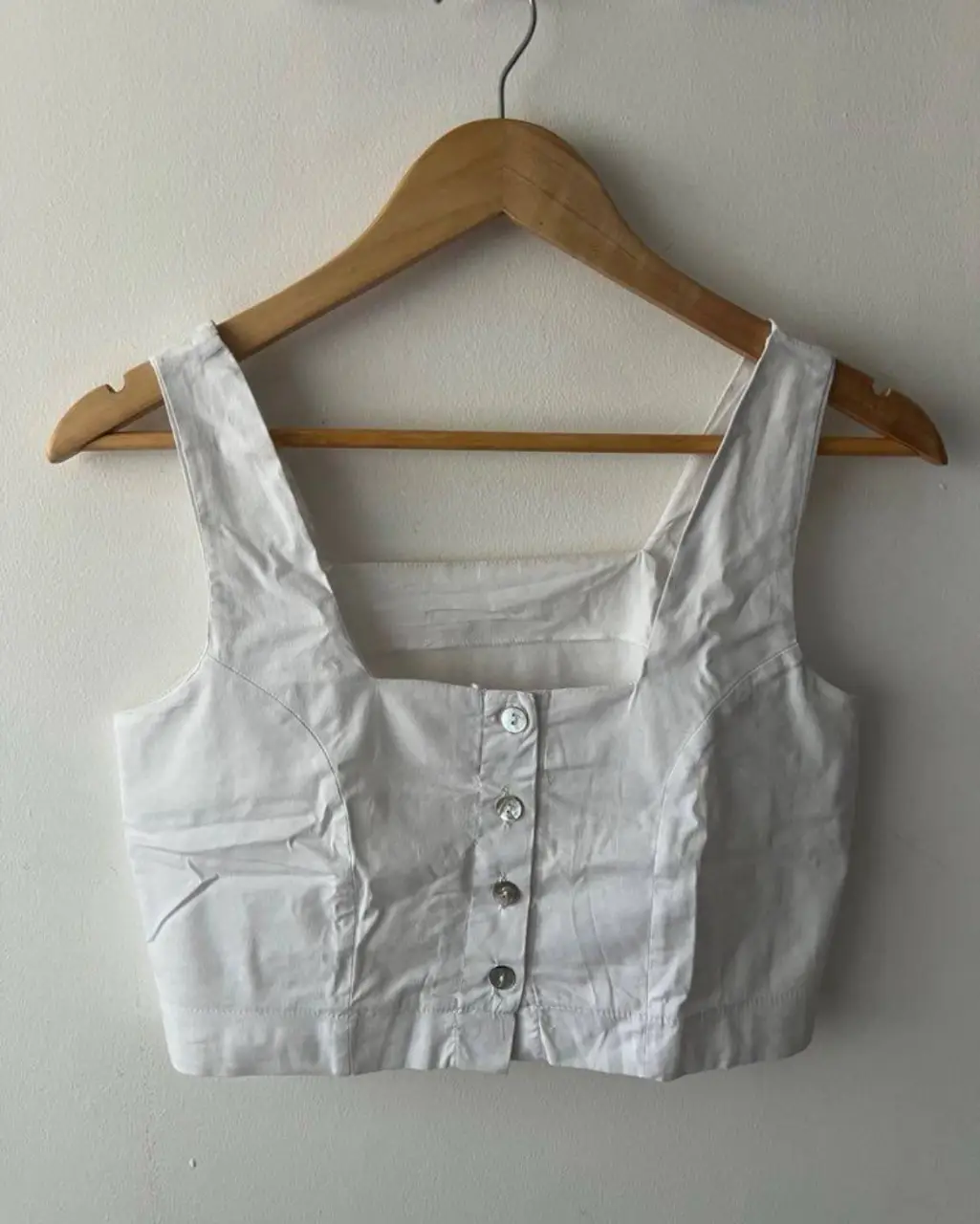 Top blanco con botones, de corte cuadrado y tirantes anchos. Ideal para un look casual y fresco.