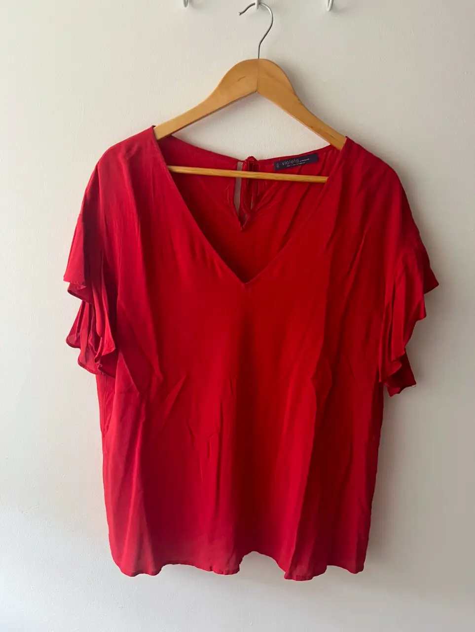 Blusa roja de manga corta con volados en las mangas y escote en V. Ideal para un look elegante y femenino.