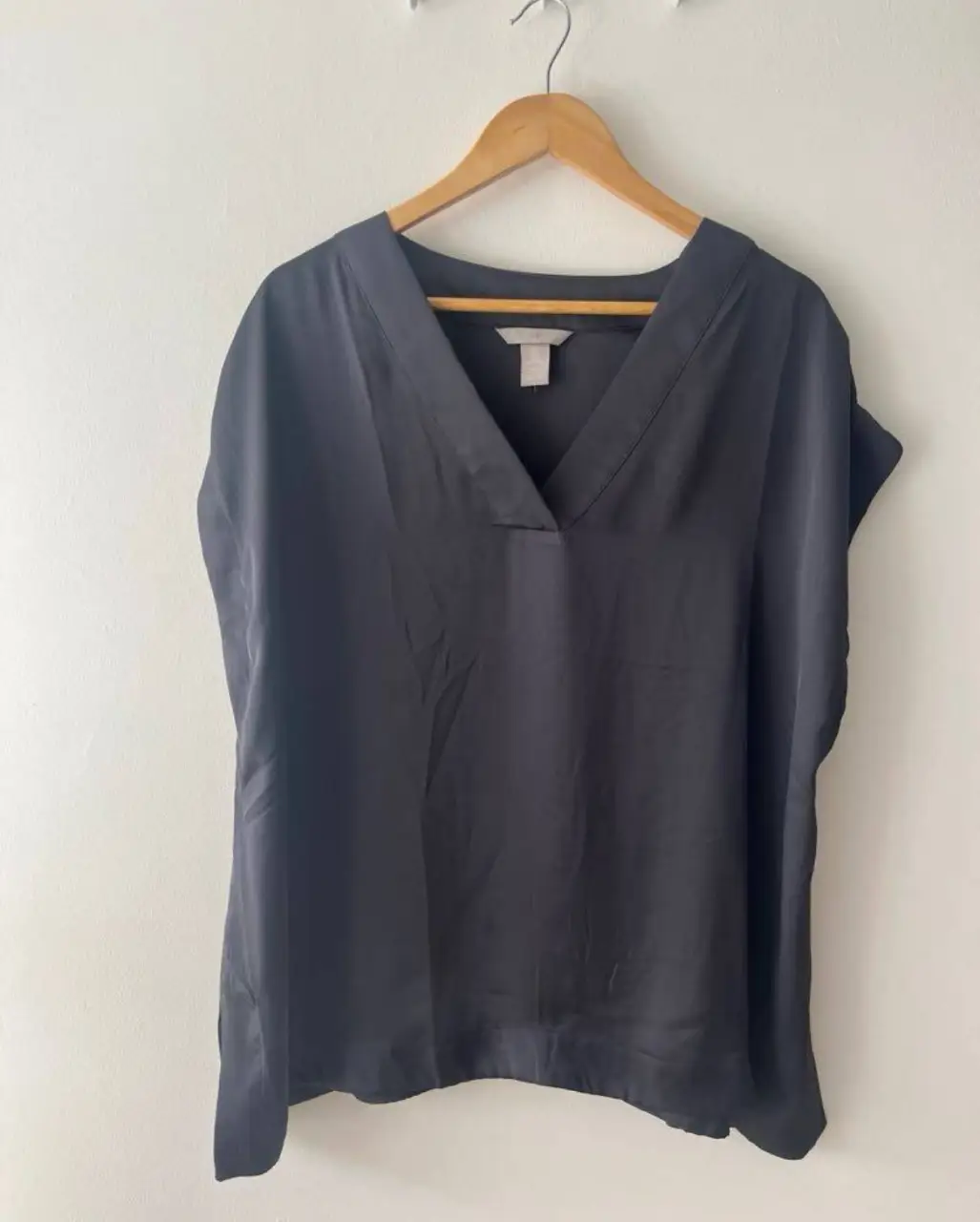 Blusa negra de H&M, con cuello en V y mangas cortas. Ideal para un look elegante y versátil.