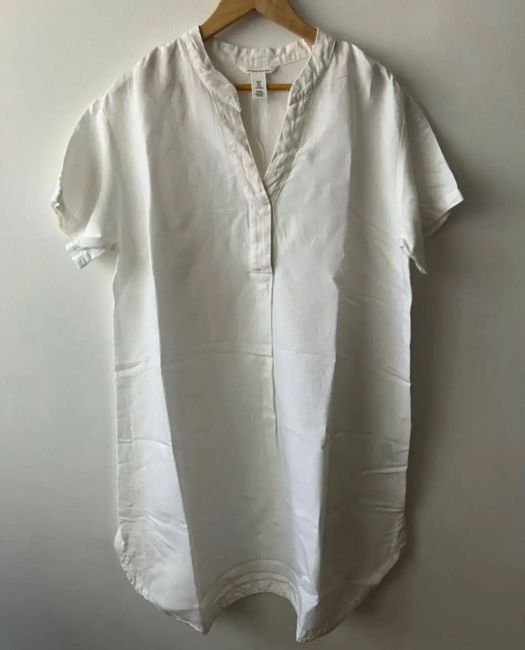 Vestido midi blanco de lino, con cuello en V y mangas cortas. Ideal para un look fresco y casual.