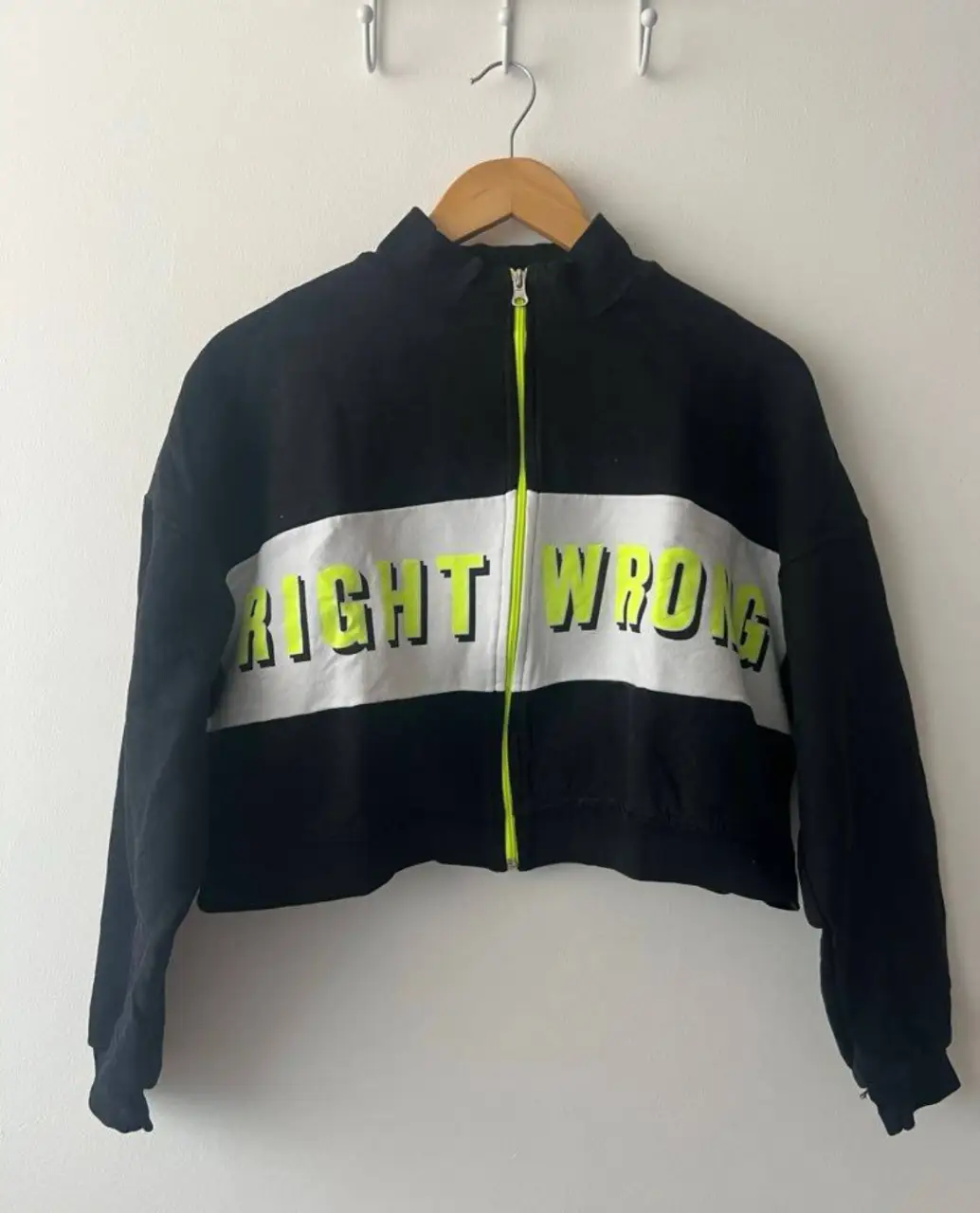 Buzo con cierre negro con detalles en blanco y amarillo flúor. Estampado "RIGHT WRONG". Ideal para un look casual y moderno.
