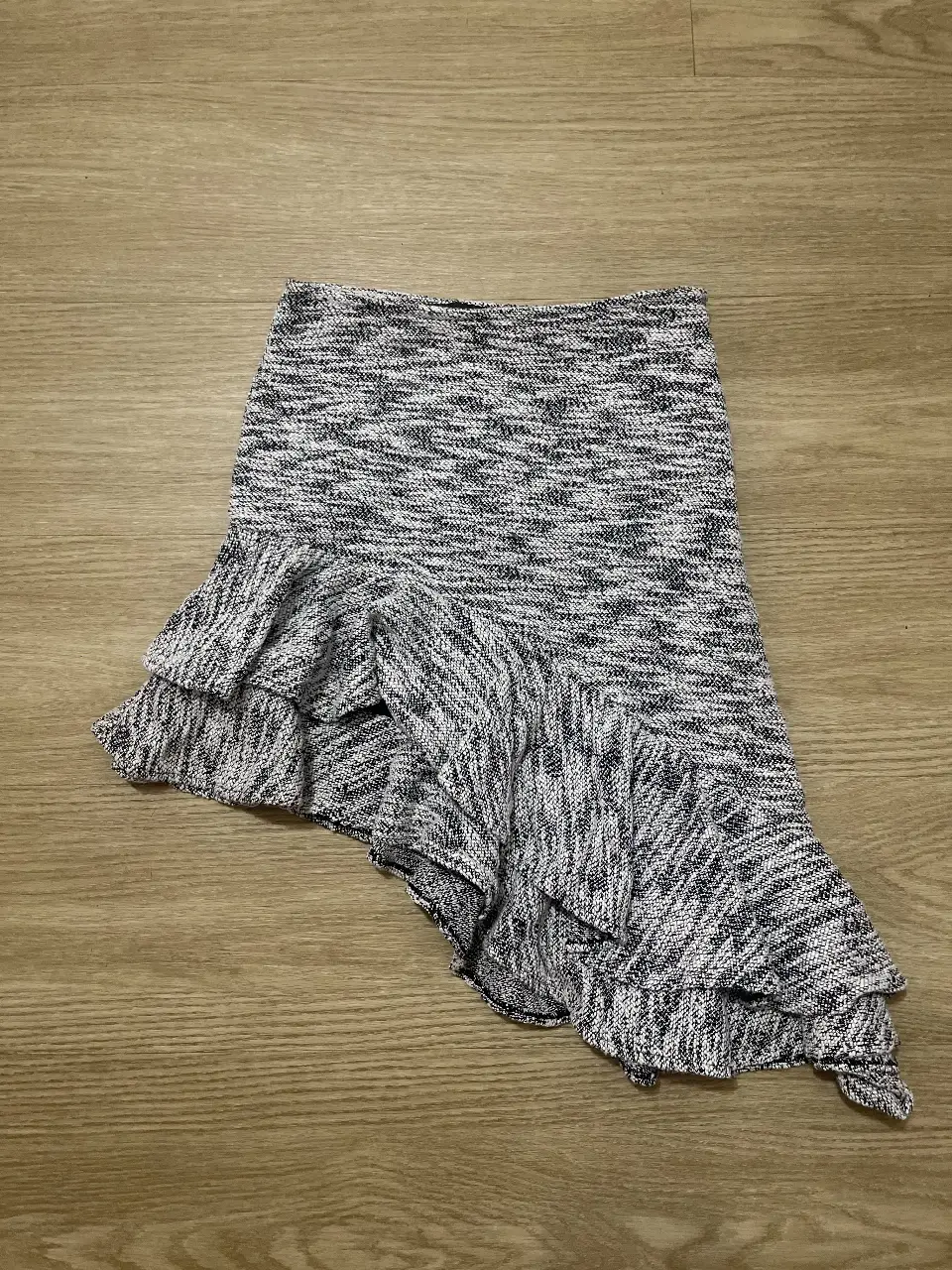Pollera asimétrica con volados. Confeccionada en un tejido jaspeado en tonos grises y blancos