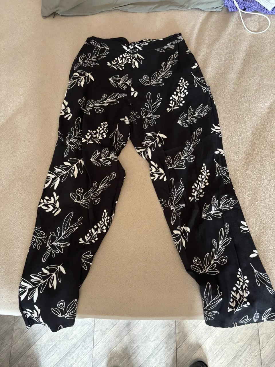 Pantalón negro con estampa de hojas blancas. Tiro alto, corte ancho y súper cómodo. Ideal para un look relajado y canchero.