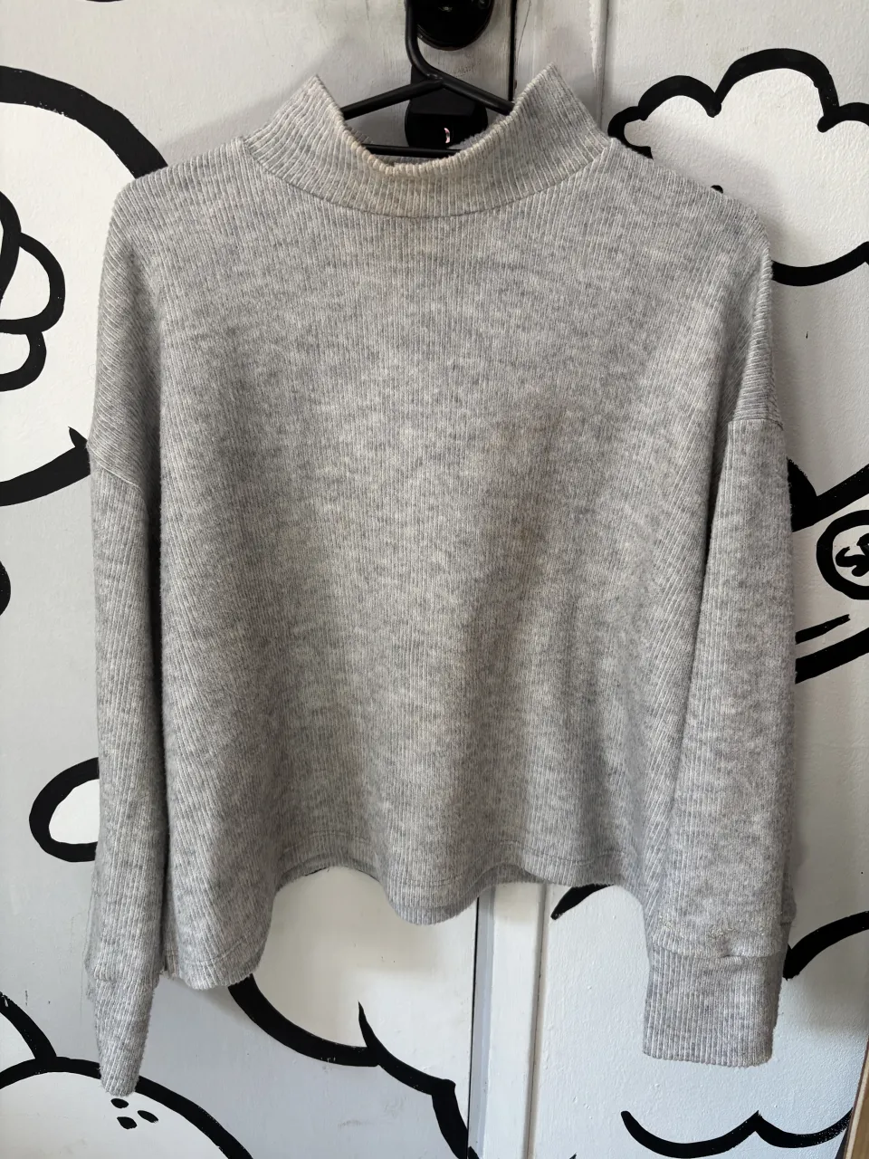 Sweater gris de cuello alto, tejido acanalado y corte moderno. Ideal para un look casual y cómodo.