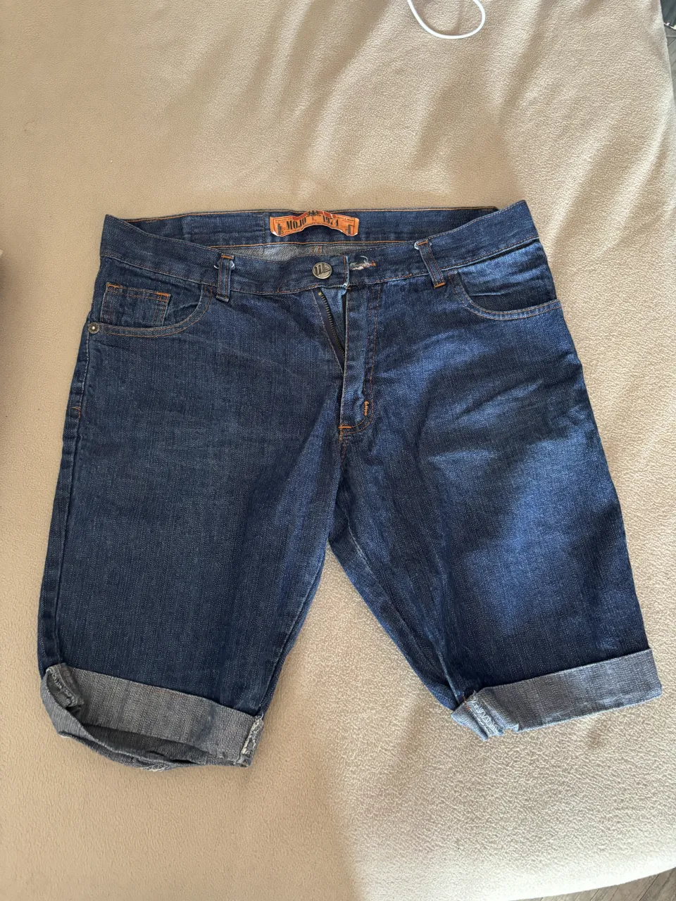 Shorts de jean tiro alto, con un lavado oscuro y detalles de desgaste sutiles. Poseen bolsillos funcionales y un diseño moderno, ideales para un look casual y canchero.