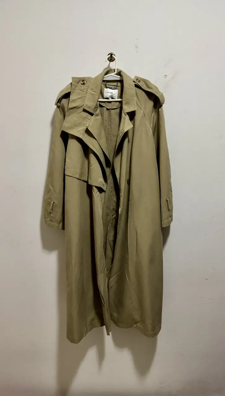 Trench coat largo color khaki, con solapas. Ideal para un look elegante y sofisticado.