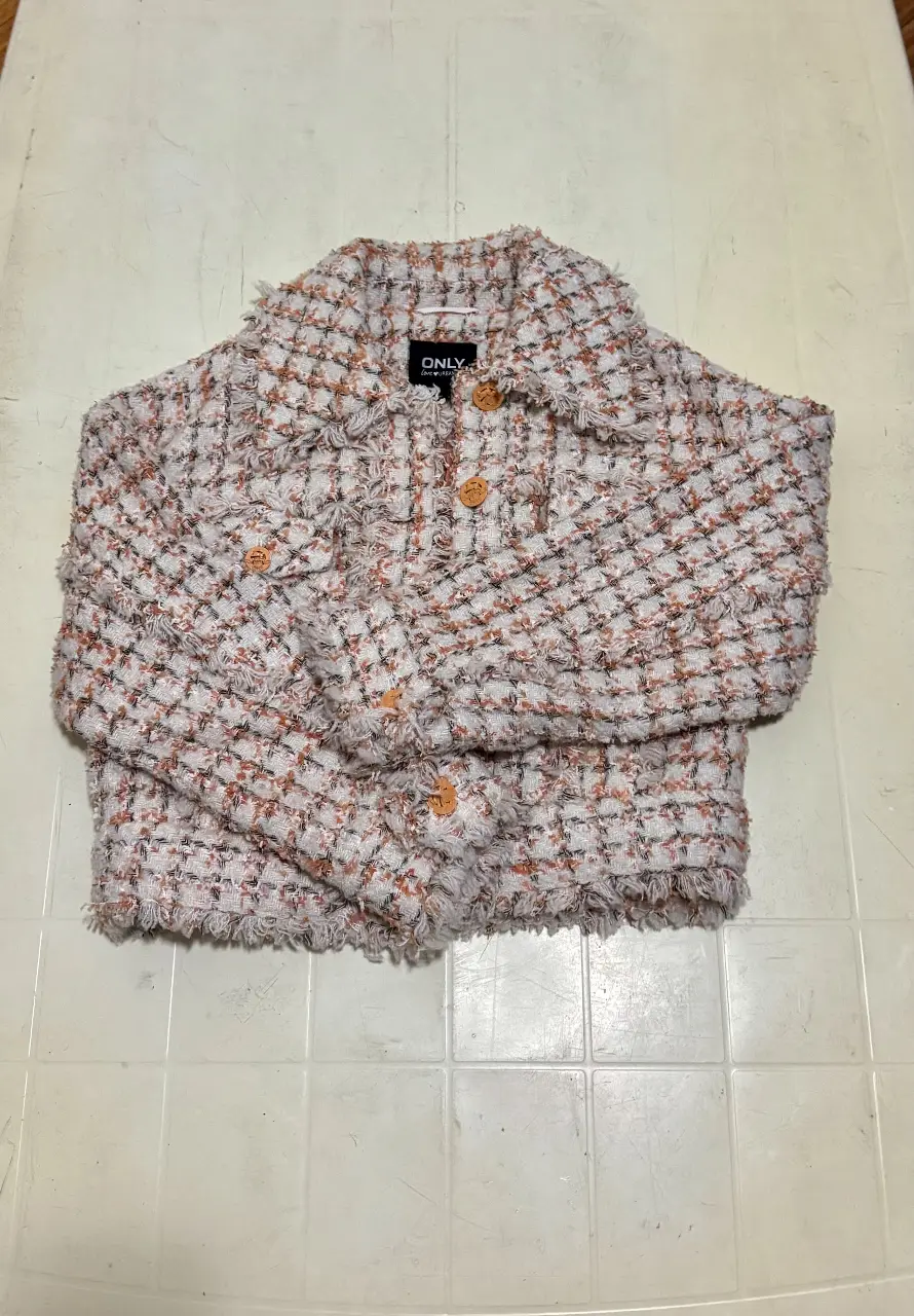 Campera tipo bomber de tela tweed con detalles en naranja y blanco. Ideal para un look elegante y canchero.