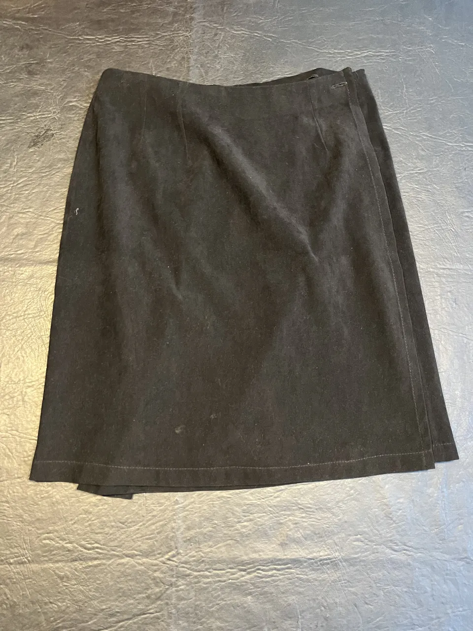 Pollera sastrera de terciopelo negra, con detalle de solapa y botón. Ideal para un look elegante y sofisticado.