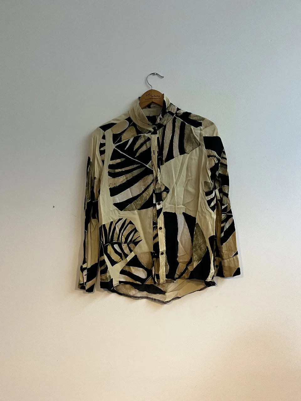 Camisa estampada con diseño abstracto en tonos crudos y negro. Ideal para un look casual con un toque artístico. Talle S.