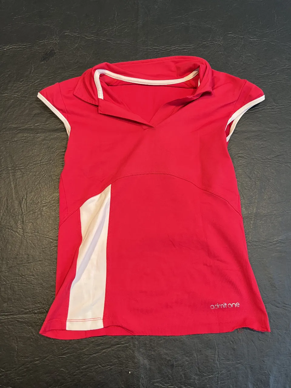 Remera deportiva roja con detalles blancos. Cuello en V y mangas cortas. Ideal para actividades físicas.