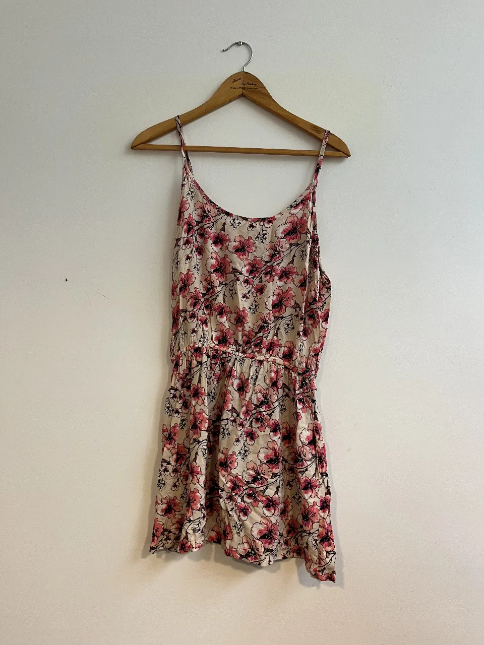 Vestido corto de mujer con estampado floral en tonos rosa y blanco. Tiene tirantes finos y cintura elastizada. Ideal para el verano.