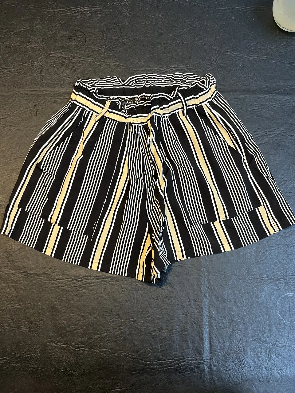 Shorts de mujer a rayas verticales en blanco y negro, tiro alto, con cintura elastizada y detalle de lazo. Ideal para un look casual y fresco.