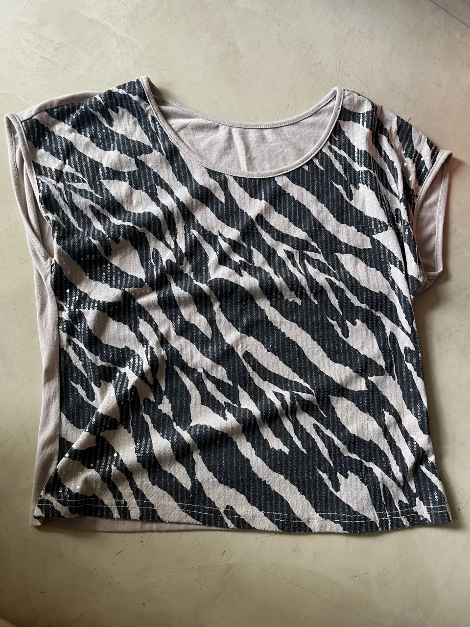 Remera de manga corta con estampa animal print de cebra en negro y beige. La parte trasera es lisa en color beige claro.