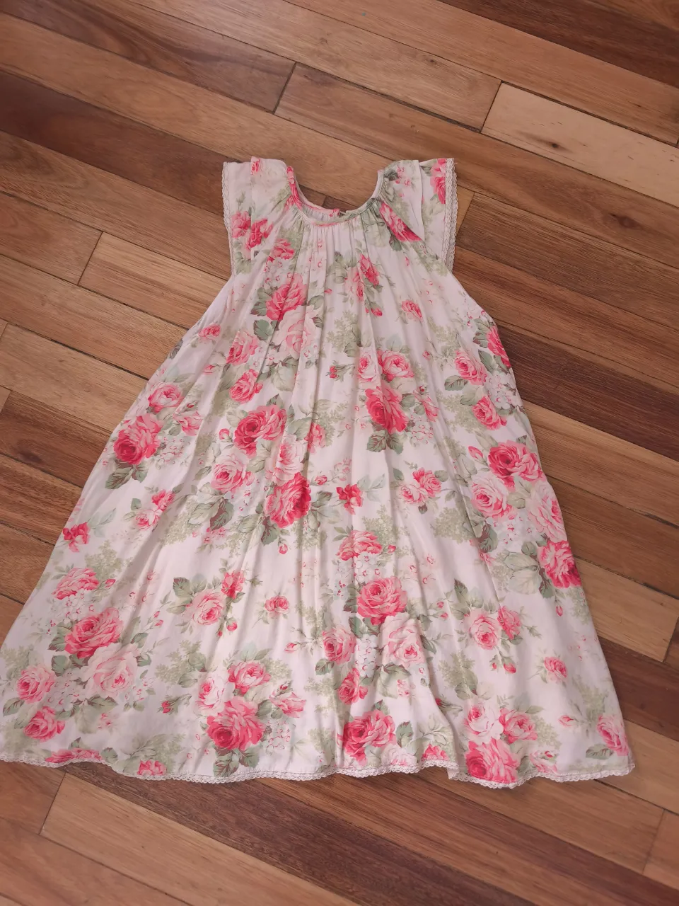 Vestido blanco con estampa floral de rosas rojas y rosas. Posee un delicado detalle de puntilla en el ruedo y en los breteles. Ideal para un look romántico y fresco.