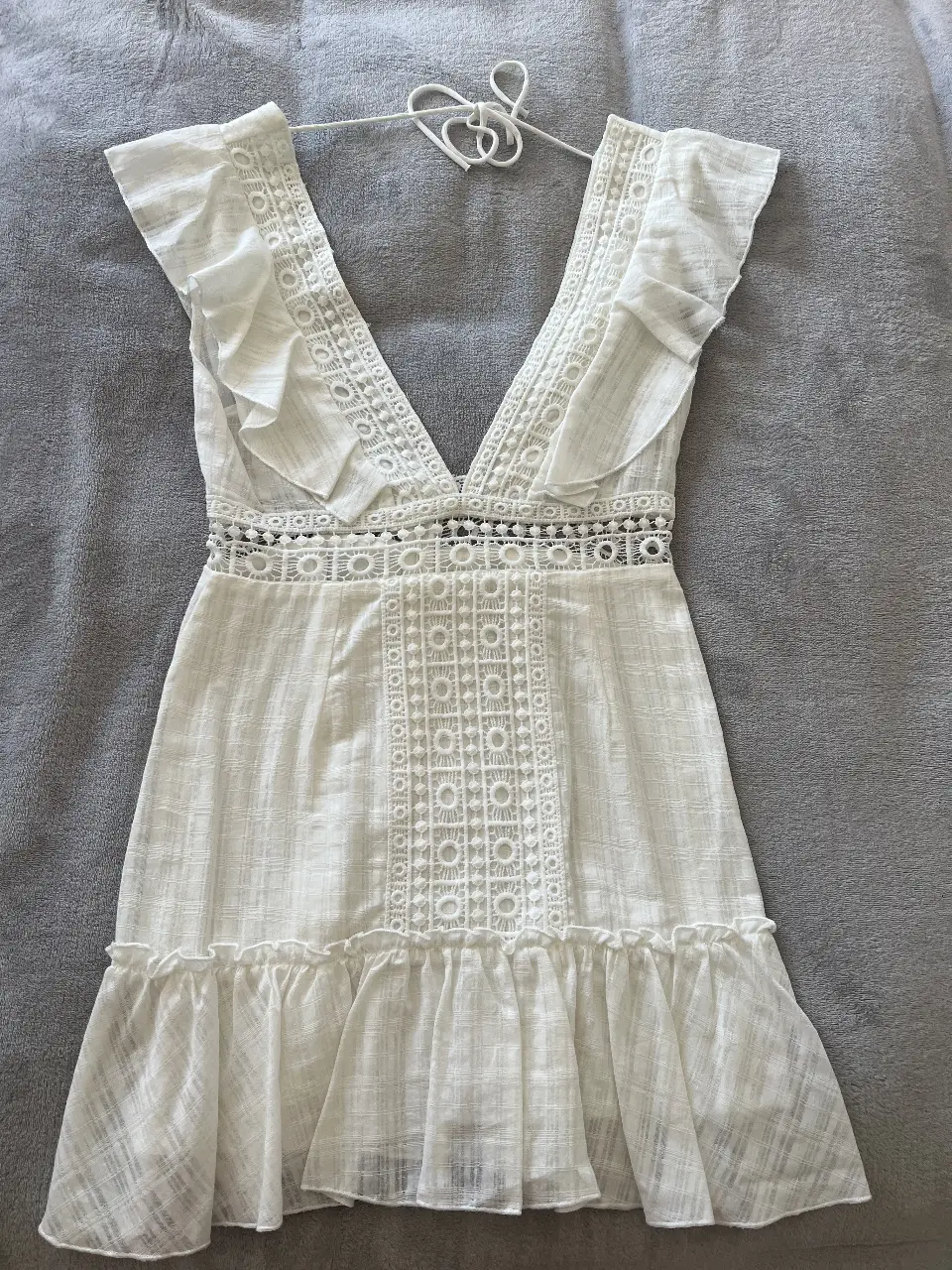 Vestido mini blanco con detalles de encaje y volados en las mangas. Ideal para un look fresco y veraniego.