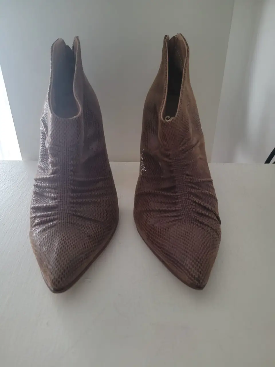 Botines de mujer color marrón con taco fino y punta. Tienen cierre en la parte trasera y detalles fruncidos en la parte delantera. Talle 7.