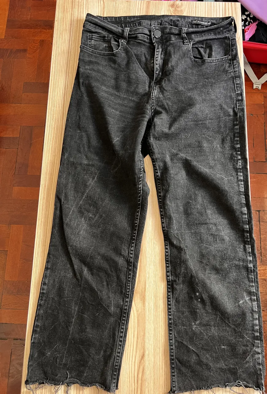 Jean de color negro con roturas y detalles desgastados en la tela. Posee dobladillo deshilachado en los bajos.