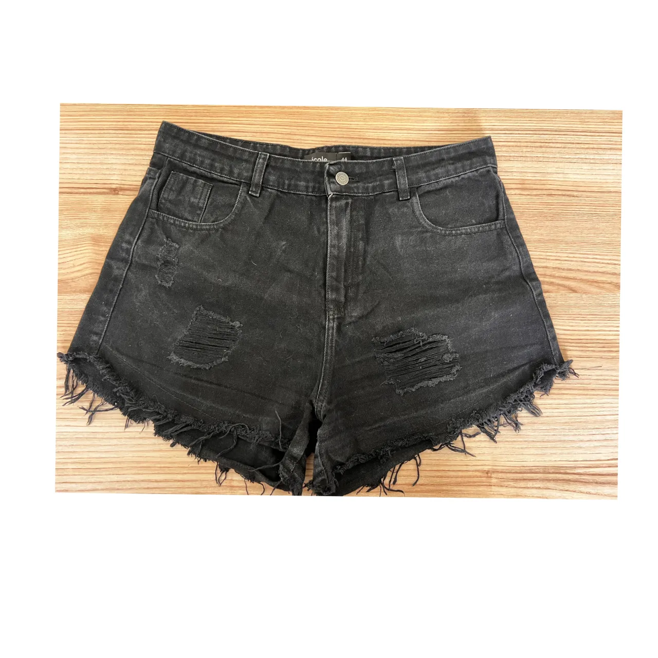 Shorts de jean negros con roturas y detalles deshilachados en los bordes.