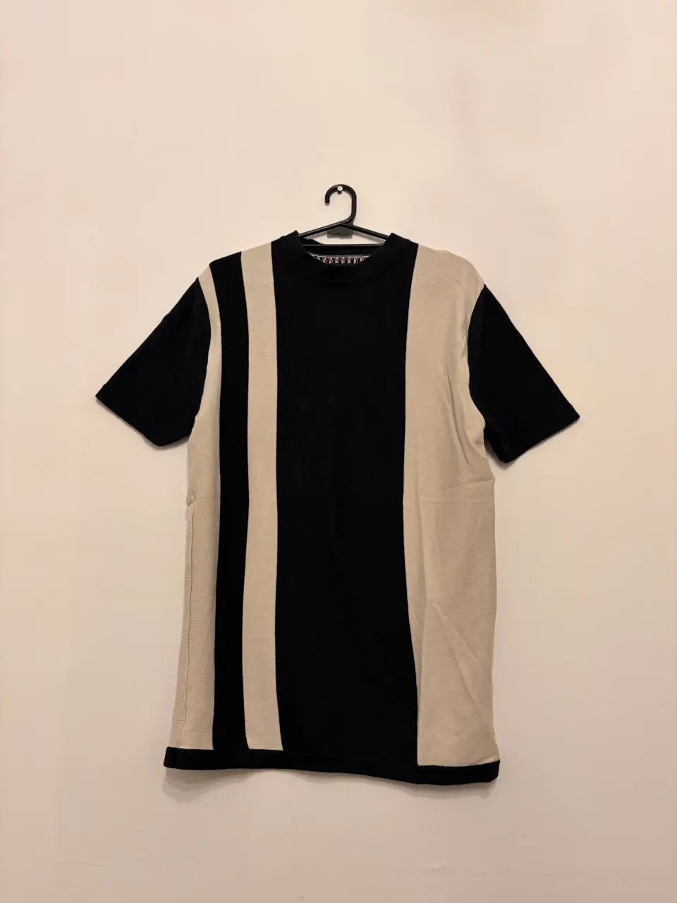 Remera de manga corta con un diseño de rayas verticales en color negro y crudo. Ideal para un look casual y moderno.