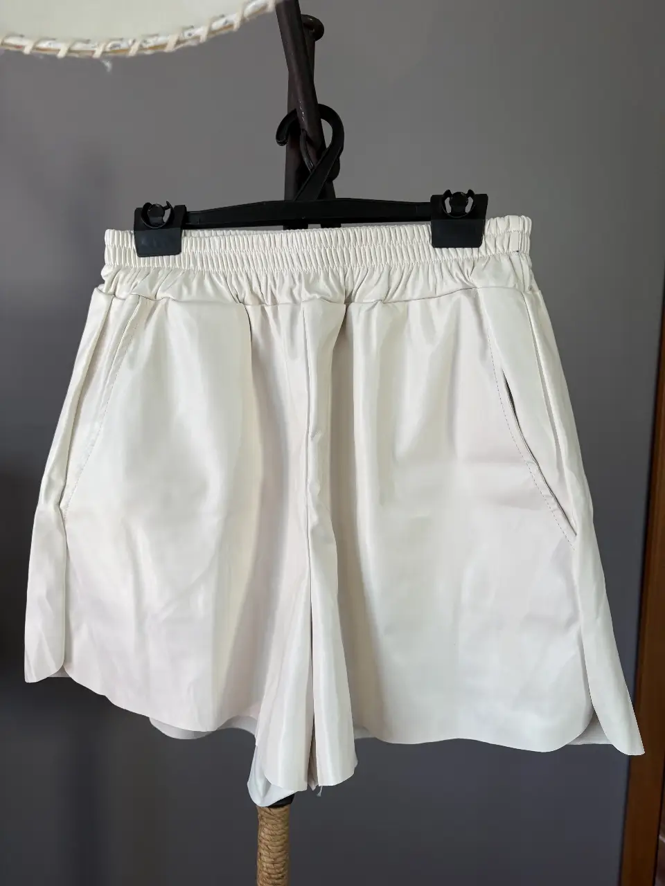 Shorts tiro alto de cuero sintético blanco, con cintura elastizada y bolsillos laterales. Interior forrado. Ideal para un look moderno y versátil.