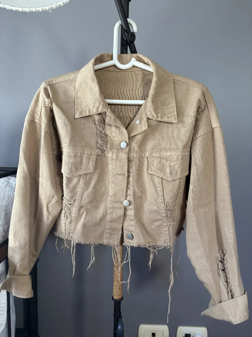 Campera de jean color marron claro con detalles rotos y flecos en el borde. Ideal para un look casual y canchero.