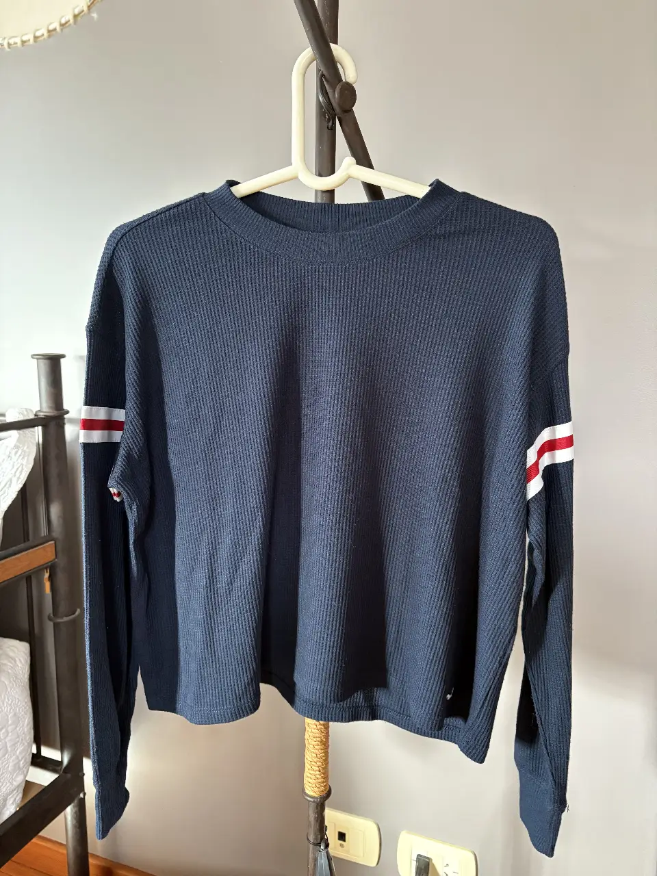 Sweater  azul marino de la marca Hollister, con detalles en blanco y rojo en las mangas. Talle XS, ideal para un look casual y cómodo.