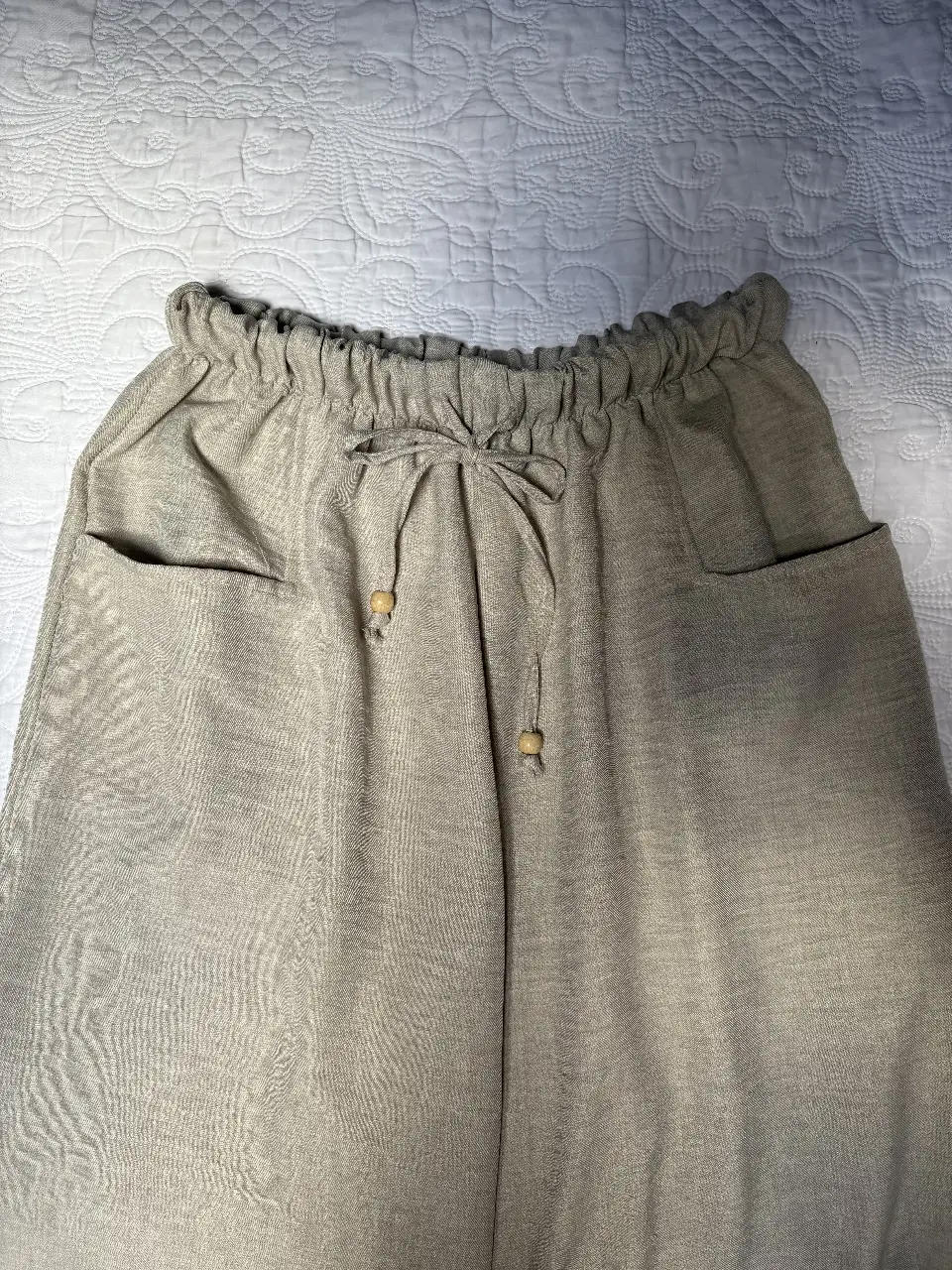 Pantalón suelto de lino color gris, con cintura elastizada y cordón para ajustar. Posee bolsillos laterales y un diseño cómodo y fresco, ideal para un look casual y relajado.