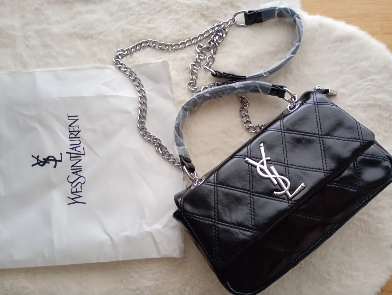 Bolso negro acolchado con cadena plateada, ideal para complementar cualquier look.