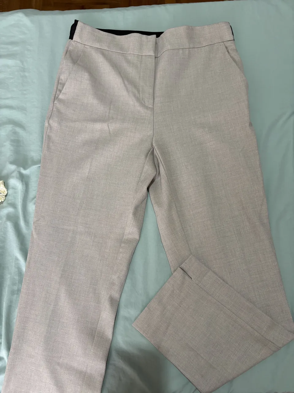 Pantalón de vestir color gris claro con bolsillos delanteros y cierre con botón.