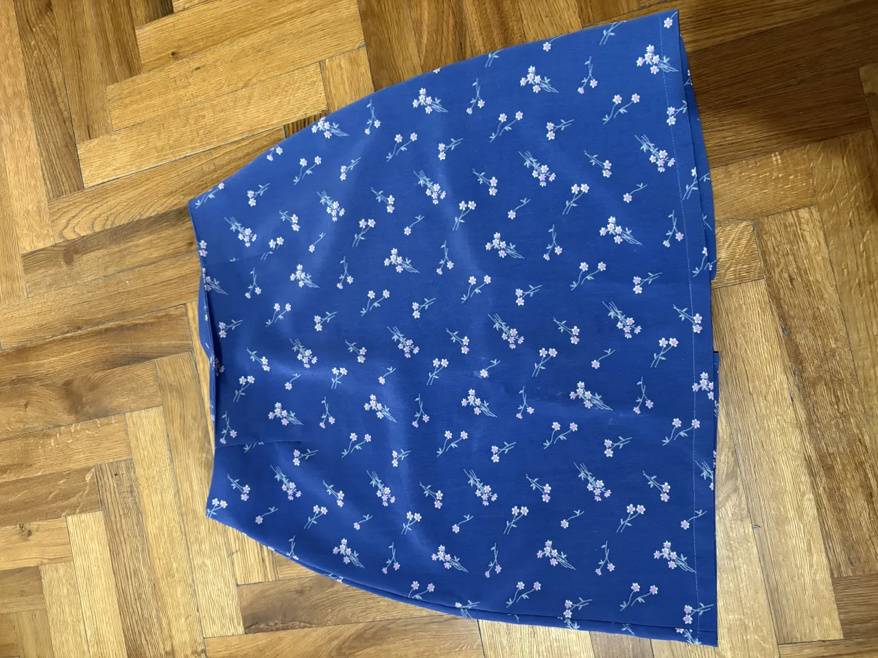 Pollera azul con estampa de flores blancas y detalles en rosa.