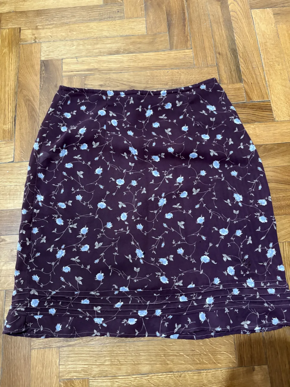 Pollera vintage corta con estampa floral de flores celestes, con forro interno. Posee un detalle de frunces en el ruedo.