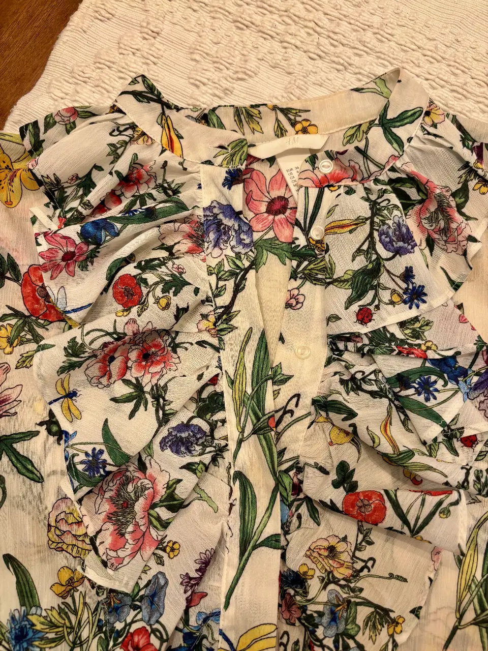 Blusa de mujer con estampado floral, detalles de volantes y botones. Ideal para un look fresco y primaveral.