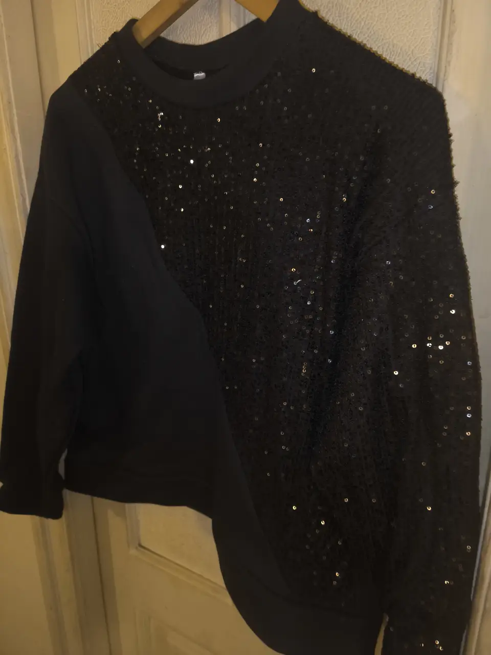 Buzo de cuello redondo negro con detalle de lentejuelas en diagonal. Ideal para un look de fiesta o salida.
