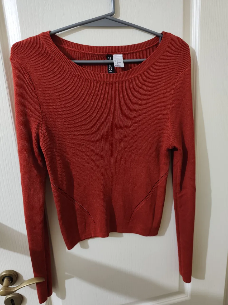 Sweater fino de manga larga, escote redondo, color rojo. Posee detalles de costura en diagonal en la parte inferior del frente.