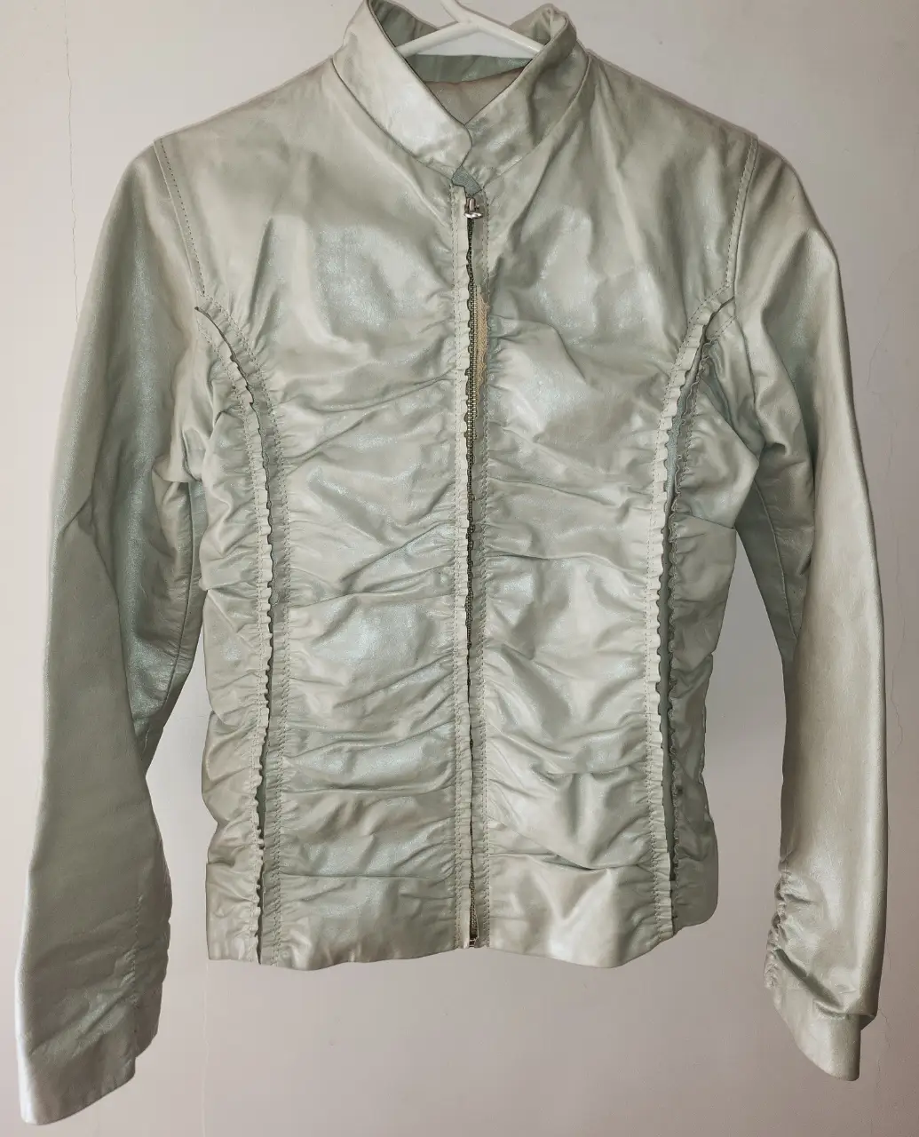Campera de cuero VACUNO gris perla (nacarada) con detalles fruncidos en la espalda y frontal. Ideal para un look moderno y versátil.