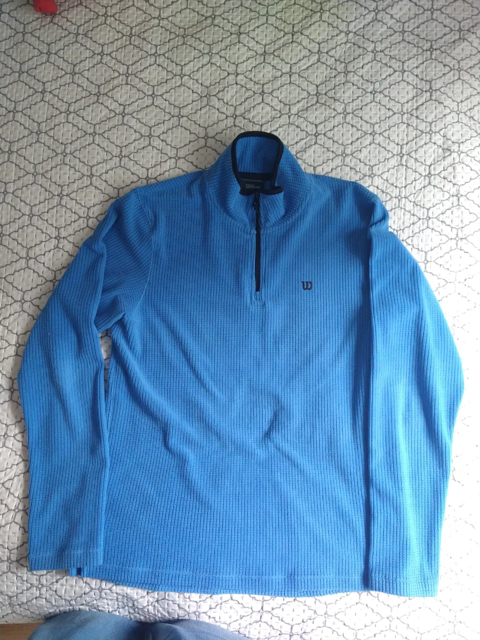 Buzo azul de manga larga con cuello alto y cierre al frente. Posee un logo pequeño bordado en el frente.