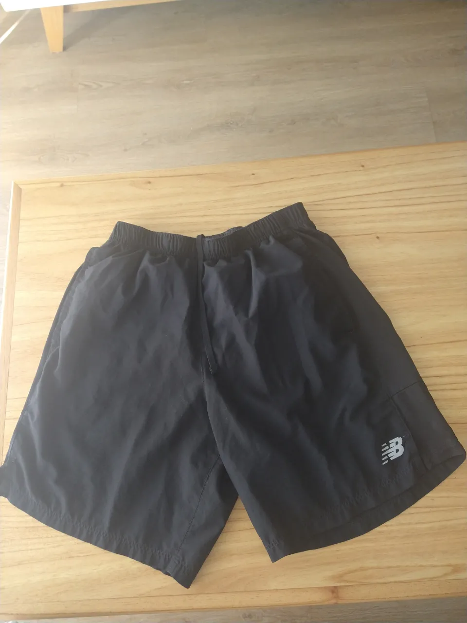 Shorts deportivos negros con logo de la marca en plateado.
