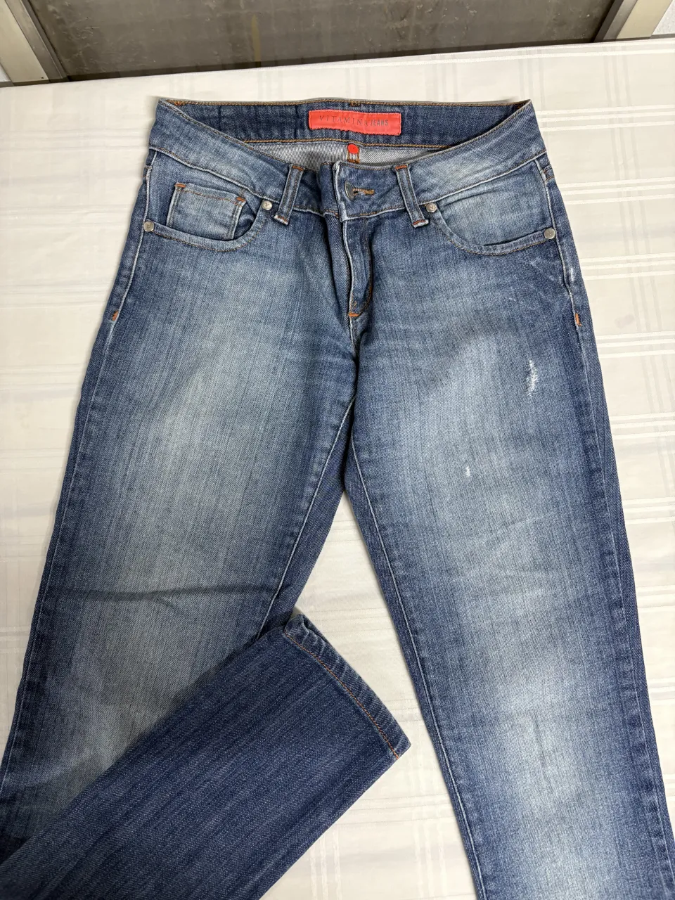 Jeans de corte recto, tiro medio, con un lavado desgastado y detalles sutiles de roturas. Perfectos para un look casual y moderno.