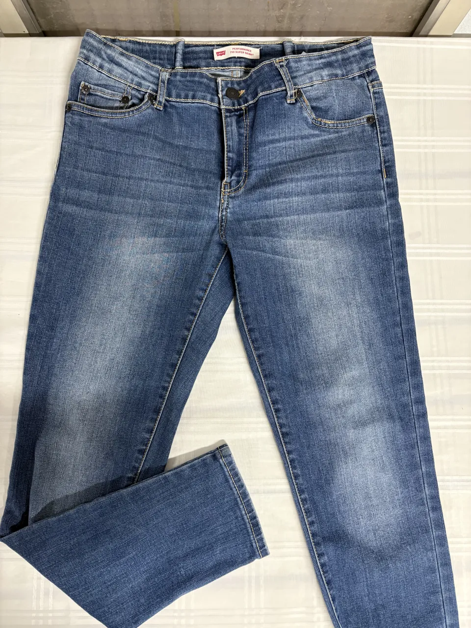 Jeans Levi's tiro alto, modelo 710 Super Skinny. Lavado clásico en tono azul medio con detalles de desgaste sutiles. Perfectos para un look casual y moderno.