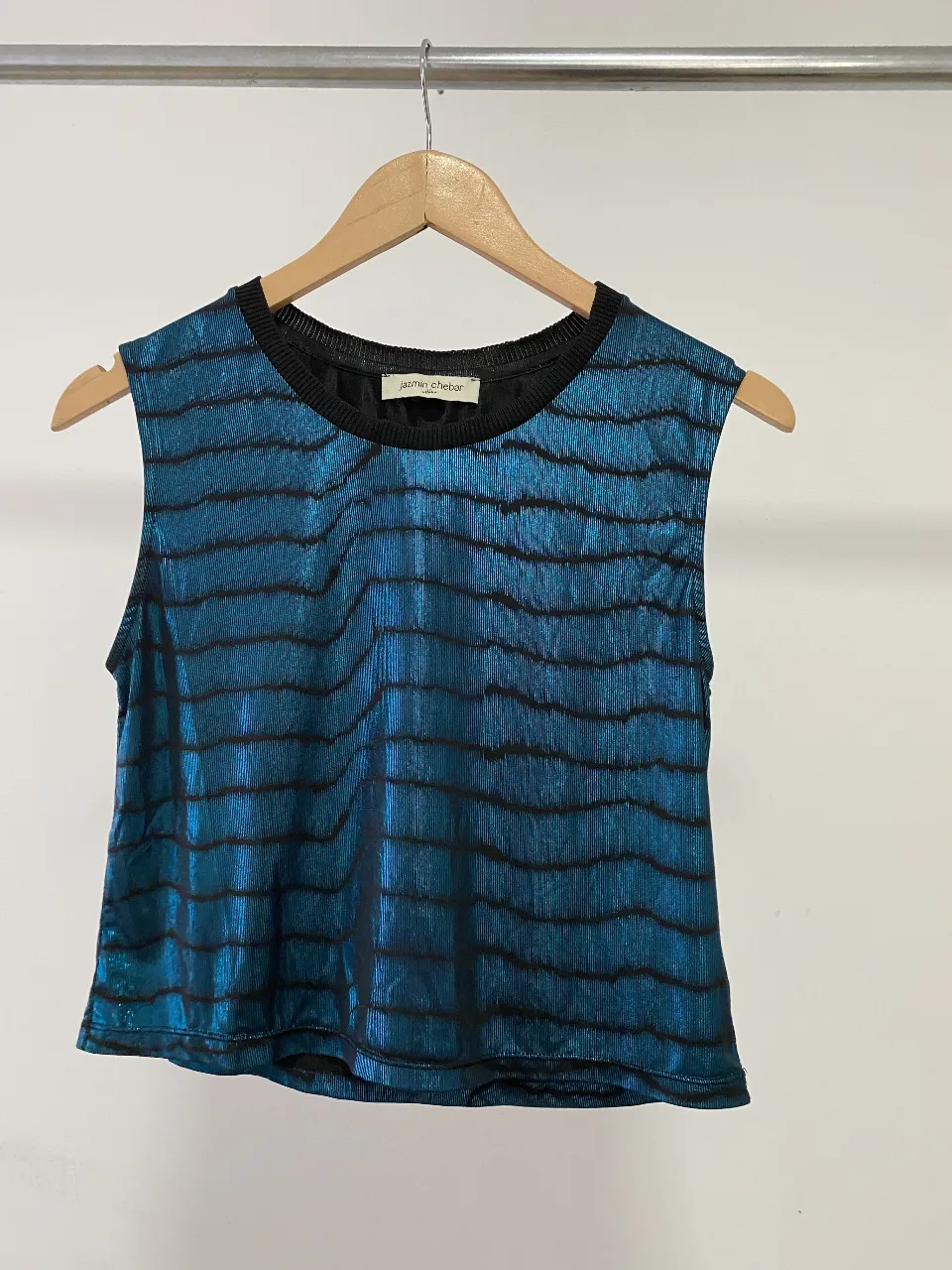 Top metálico azul con detalles en negro, ideal para un look canchero y moderno. Su diseño sin mangas y corte moderno lo hacen perfecto para salidas nocturnas o eventos informales.