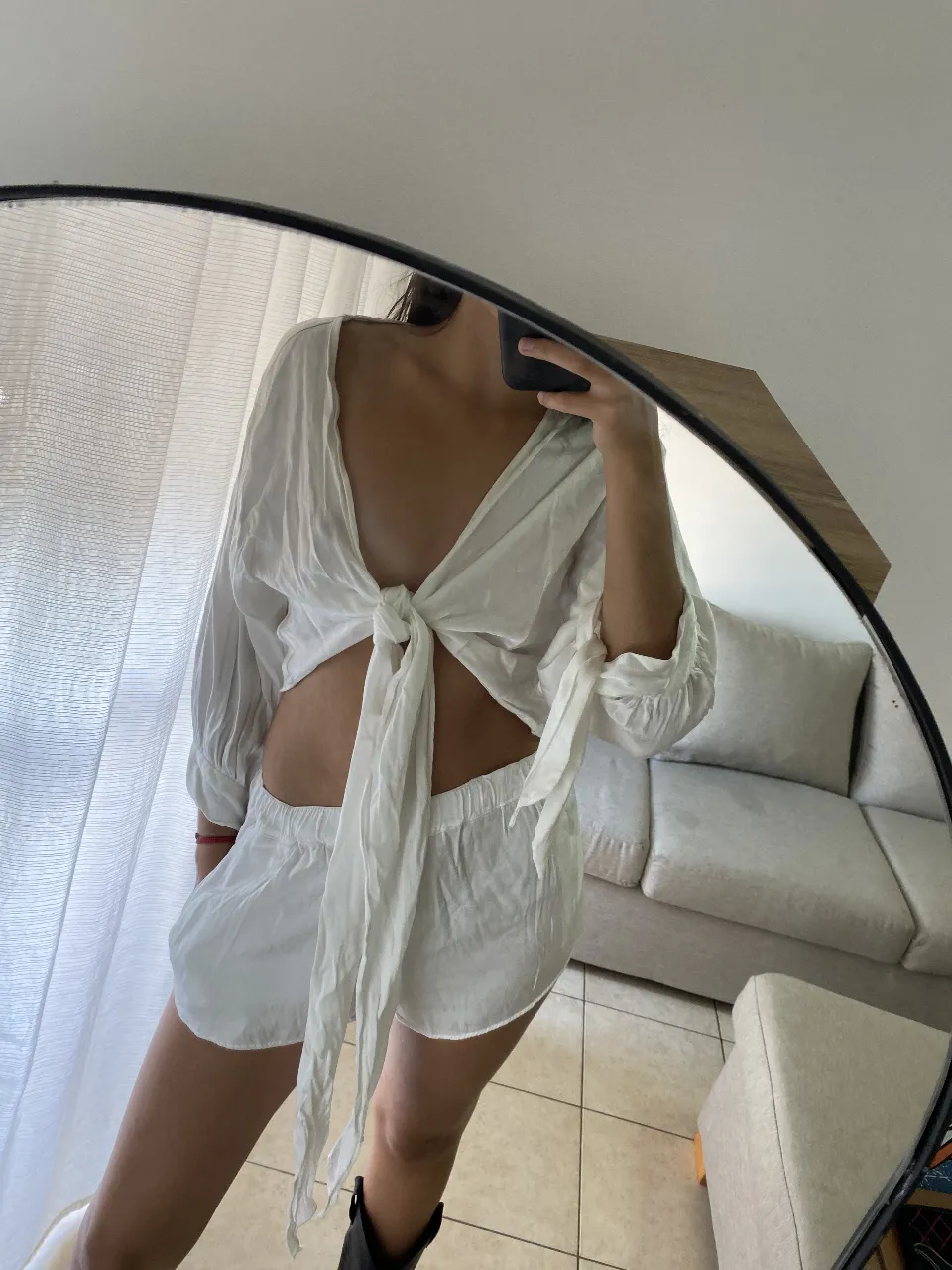 Conjunto de dos piezas blanco, ideal para el verano. El top es un diseño con lazo en el frente y mangas largas. El short es de tiro alto y suelto, perfecto para un look fresco y cómodo.
