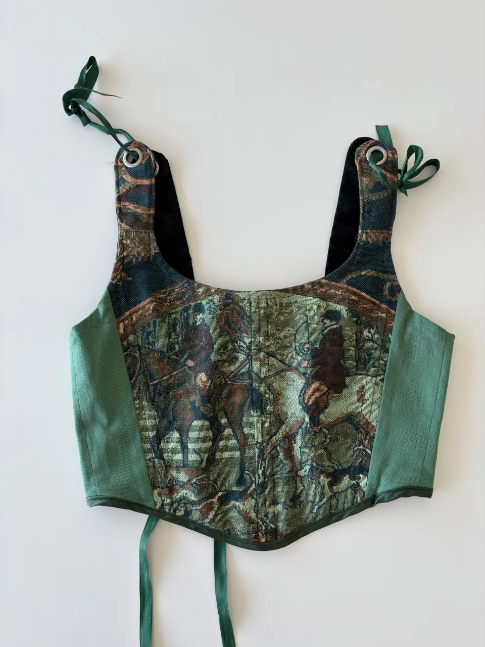 Corpiño estilo corsé con estampado de escena ecuestre vintage. Diseño único con tiras regulables y lazo en la espalda para un ajuste perfecto. Ideal para un look audaz y con carácter.