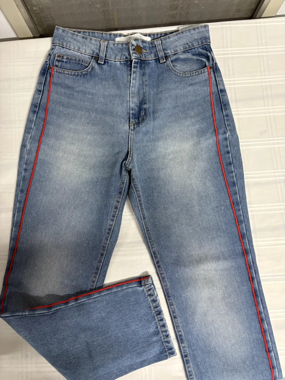 Jeans tiro alto con detalles de franja roja en los laterales. Un clásico reinventado para un look moderno y canchero. Ideales para combinar con tops o remeras básicas.