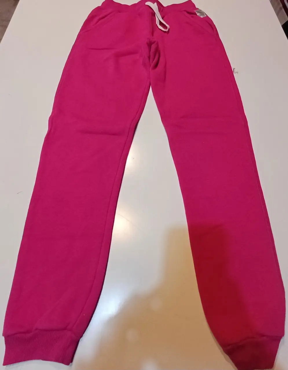 Pantalón de jogging rosa chicle, ideal para un look casual y cómodo. Confeccionado en tela suave, este pantalón es perfecto para el día a día. Cuenta con cintura elastizada y bolsillos.