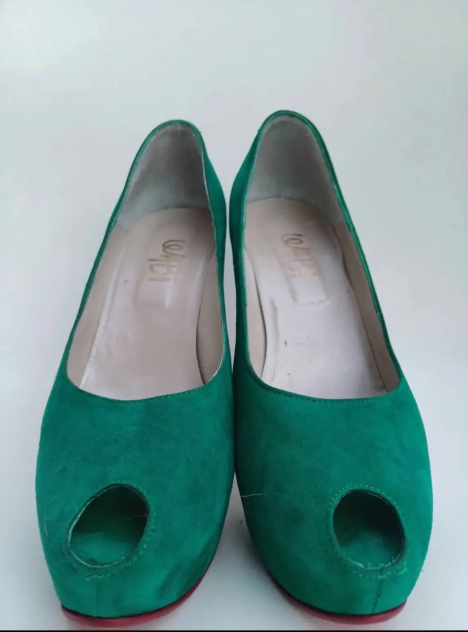 Elegantes zapatos de tacón alto en gamuza verde esmeralda con detalle de peep toe. Suela roja y diseño sofisticado, ideales para eventos especiales.